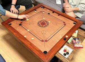 A photo of two people at a carrom board.